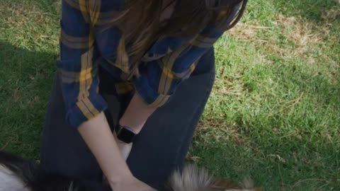 Woman petting her dog on the lawn