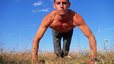 Shirtless man doing push-ups in the countryside