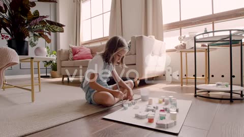 Blonde Girl Sitting On The Floor And Painting Animal Pieces In Living Room 1