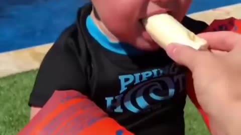 Child tries to eat a banana but fails