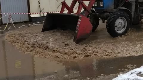 Hard Russian tractor accelerates puddle