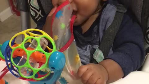 Baby desperately pulls on his bib to take it off