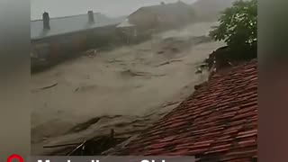 A scary scene of surging flood water rushing into the village filmed by a villager from a rooftop