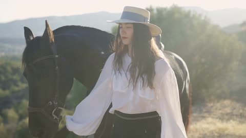 Side view of confident horsewoman in straw hat and graceful animal