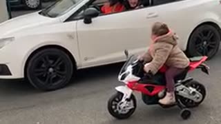 Kid on Toy Motorbike Challenges Driver to a Race