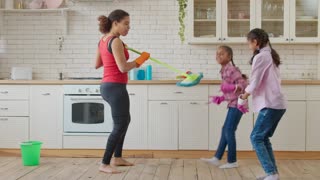 mother and daughters in a kitchen dancing
