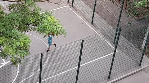 Boy playing basketball, another playing phones