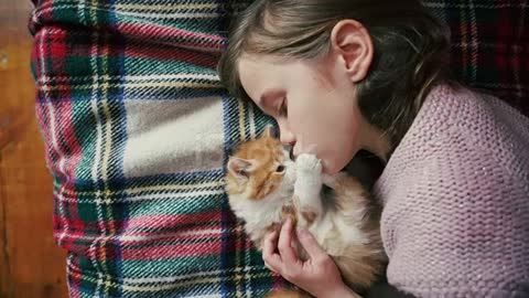 فتاة صغيرة تلعب مع قطة على السرير