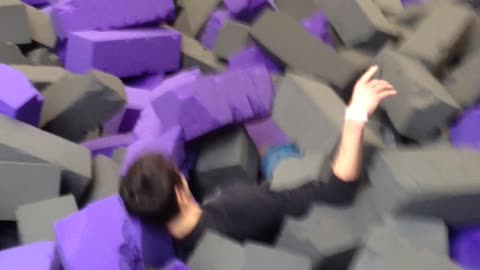 Music kid flips into soft grey and purple foam pit