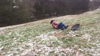 Guy on black tube holds rope while being pulled on grass