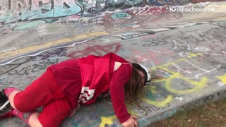 Girl in red outfit falls off skateboard