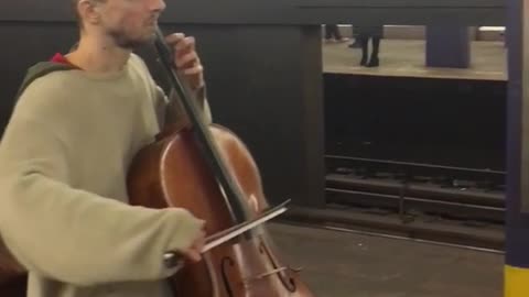 Man plays cello inside subway station, guys playing violin across station