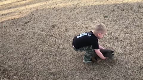 Kid hilariously struggles to pick up elusive puppy
