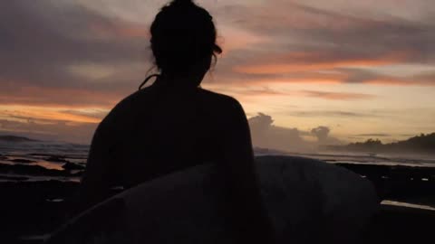 Surfer girl's silhouette at sunset_