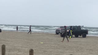 Guy in wetsuit misses yellow frisbee on beach
