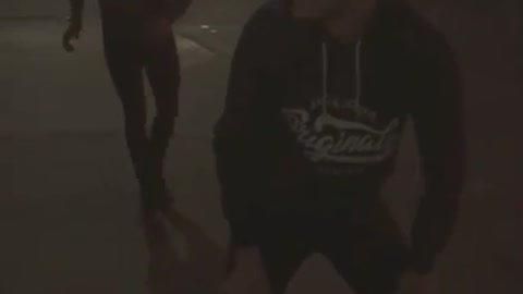 Guy on sidewalk at night tries to leap frog friend faceplants