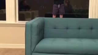 Toddler in black shirt falls over blue couch