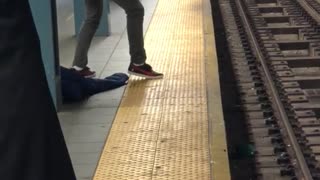 Man with long curly black hair sings on subway platform