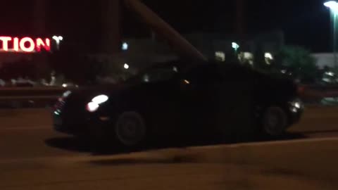 Black car with surfboard coming out of moonroof
