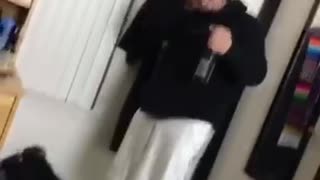 Black hoodie and white shorts opens a beer bottle and bottle cap hits him in face