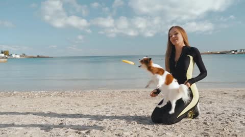 Young adult sportswoman playing with little dog outdoor