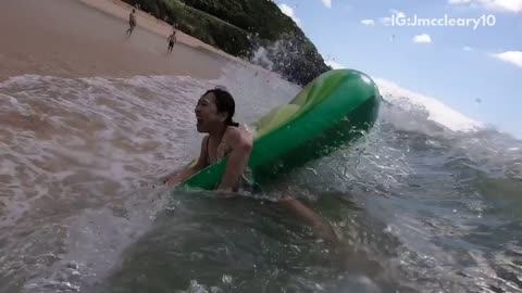 Woman in avocado floaty is flipped by wave