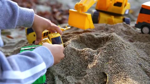 a child's hand playing sand with a toy