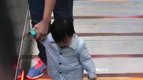 Little girl held by man walking on escalator