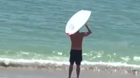 Man lifting his white surf board on beach