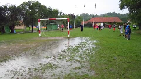 Man with hat jumps into muddy puddle in soccer field