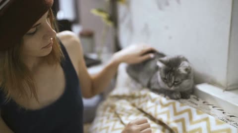 Beautiful young woman and kitten at home. Pet cat and young owner relaxing together