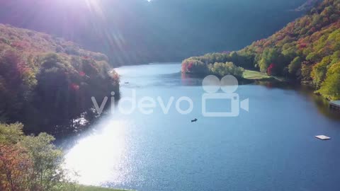 Aerial over canoe on lake surrounded by vast forests of fall foliage and color in Maine or New Engla