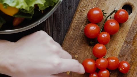 Top View of A Person Slicing Cherry Tomatoes Using a Knife