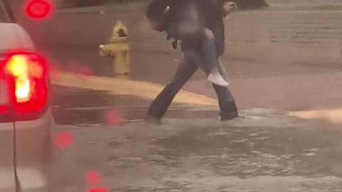 Boy Carries Fellow Students Across Flooded Street