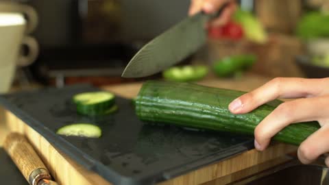 Close Up of Female Hands Slicing a Cucumber