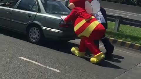 Mascot helps push broken vehicle