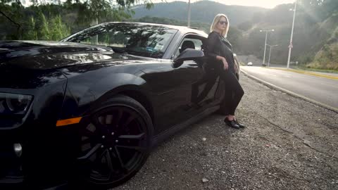 Woman leaning against luxury black car