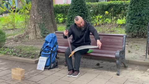 A street musician plays Titanic music on a saw