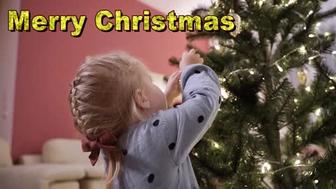 My Cute Little Girl Hanging Decors On A Christmas Tree at Home