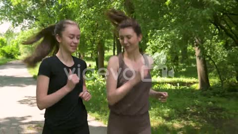 Two Pretty Sportswomen Running Outdoors In The Park