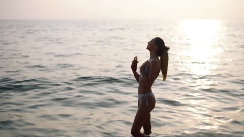 A HOT BIKINI GIRL ON BEACH ENJOYING SUNSET