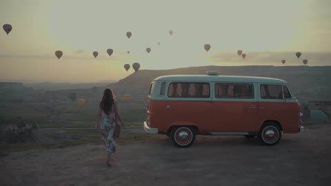 Watch Hot-Air Balloons Take to the Skies as a Woman Rides Through the Landscape Below