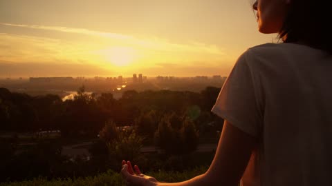 Girl meditating in yoga pose at sunset