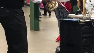 Man playing saxophone in subway station, guy dances to his music