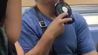 Man blue shirt uses a personal fan