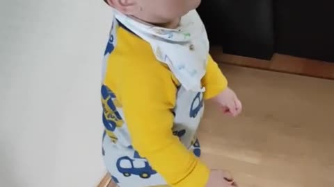 This is a video of a baby practicing standing while smiling.