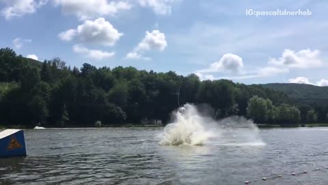 White wakeboard pulled up blue ramp body slammed into lake