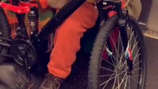 Man in orange outfit brings his bike on subway train