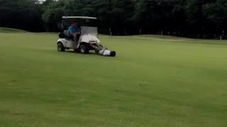 Guy laying on back being pushed by golf cart drinking beer