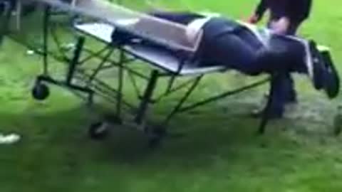 Guy in black pants and sweater jumps on ping pong table and lays there as it collapses on him
